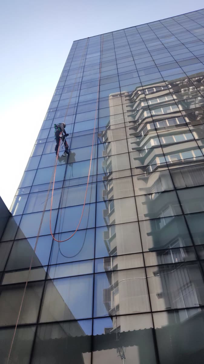 Técnico descendo pela fachada de vidro durante a limpeza